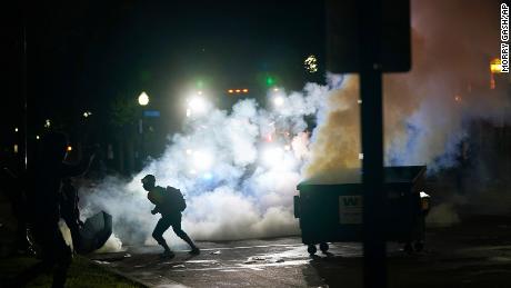 A protester moves away from a smoke canister Tuesday, Aug. 25, 2020 in Kenosha, Wis. Anger over the Sunday shooting of Jacob Blake, a Black man, by police spilled into the streets for a third night. (AP Photo/Morry Gash)