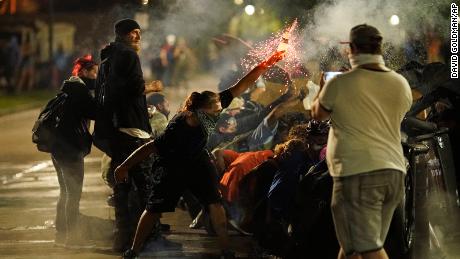 A protester tosses an object toward police during clashes outside the Kenosha County Courthouse late Tuesday in Kenosha