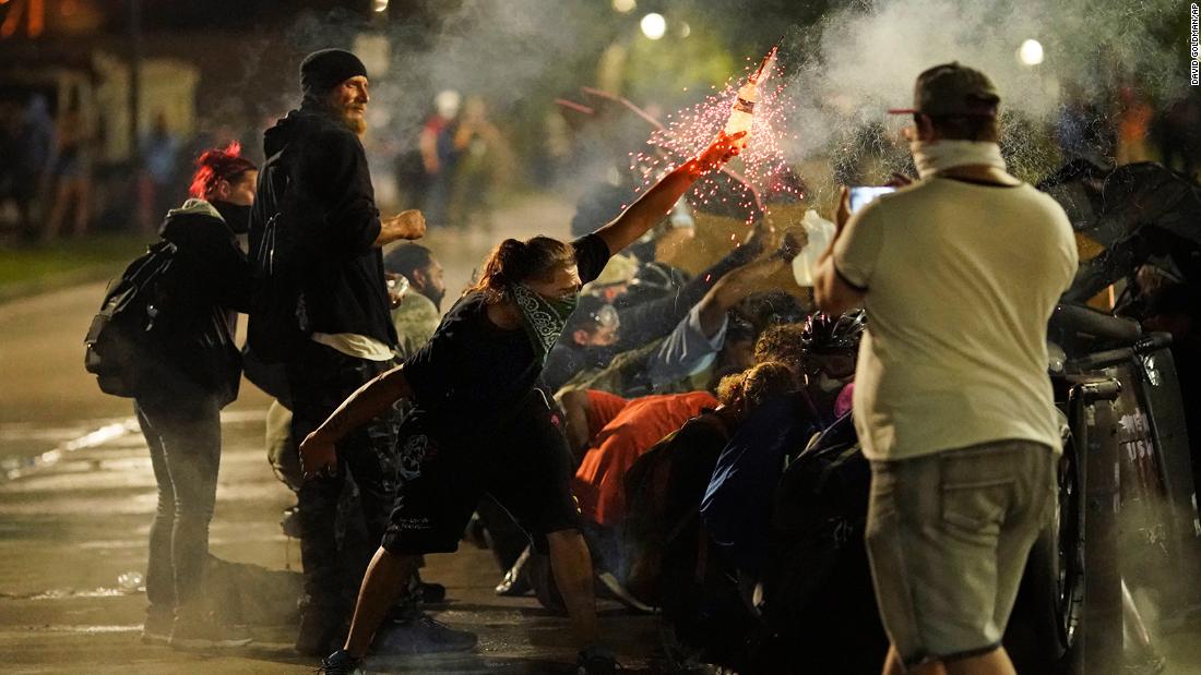 A protester tosses an object toward police during clashes outside the Kenosha County Courthouse on August 25.