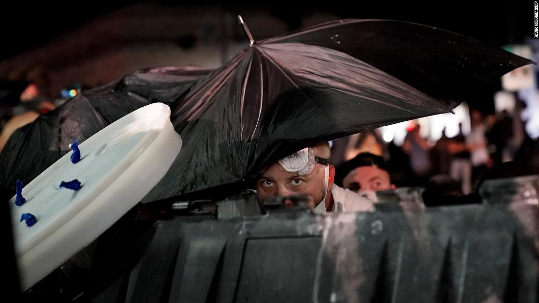 A protester takes cover during clashes outside the Kenosha County Courthouse on August 25