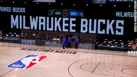 Los árbitros se paran en un asiento vacío antes del inicio de un juego programado entre los Milwaukee Bucks y Orlando Magic para el quinto juego de la primera ronda de la Conferencia Este durante los Playoffs de la NBA 2020 el 26 de agosto en Lake Buena Vista, Florida.