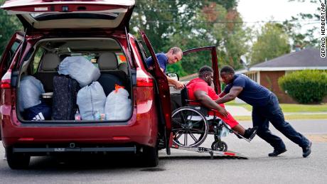 Lake Charles Fire Department personnel Alvin Taylor, right, and Jeremy Harris, left, assist Tim Williams into a transport van as he evacuates Lake Charles.