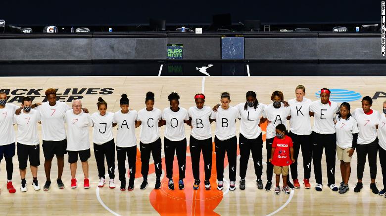 After the WNBA announcement of the postponed games for the evening, the Washington Mystics each wear white T-shirts with seven bullets on the back protesting the shooting of Jacob Blake.