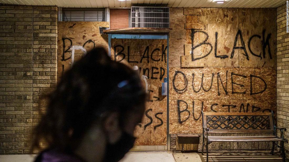 A protester walks by a boarded-up store in Kenosha on August 26.