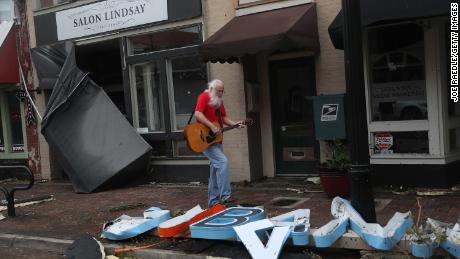 A man plays his guitar while walking through the downtown area of Lake Charles on Thursday.