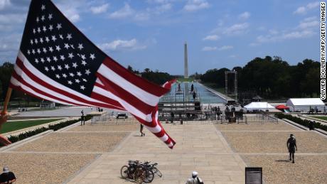 A man waves an American flag on top of the Lincoln Memorial ahead of the 2020 March on Washington.