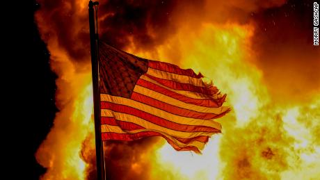 A flag flies over a department of corrections building ablaze during protests, late Monday, August 24 in Kenosha, Wisconsin, sparked by the shooting of Jacob Blake by a Kenosha Police officer a day earlier. 