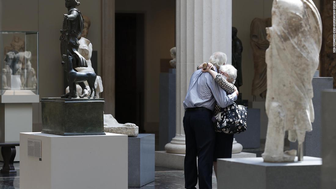 People wearing face masks hug at New York&#39;s Metropolitan Museum of Art as it reopens to members on August 27.