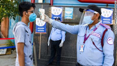 A student gets their temperature taken at an examination center in Noida, India.