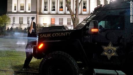 A protester obstructs an armored vehicle attempting to clear the park of demonstrators during clashes outside the Kenosha County Courthouse on August 25.