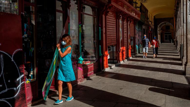 A woman wearing a mask opens a retail store in central Madrid, Spain, on September 3, as cases surge in the region.