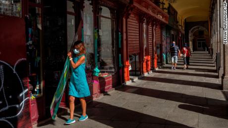 A woman wearing a mask opens a retail store in central Madrid, Spain, on September 3, as cases surge in the region.