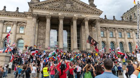 Protesters stand in front of German riot policemen who stand guard at the Reichstag building in Berlin as demonstrators tried to storm in at the end of a demonstration called by far-right and COVID-19 deniers to protest against restrictions related to the new coronavirus pandemic, in Berlin, on August 29, 2020.  (Photo by )