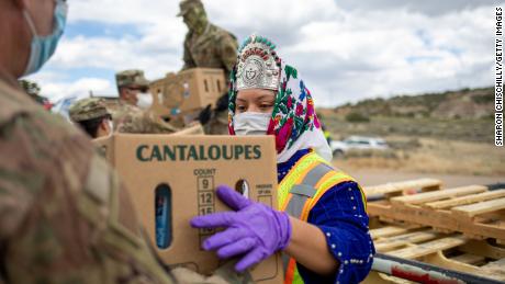 Miss Navajo Nation Shaandiin Parrish grabs a box filled with food and other supplies to distribute to Navajo families.