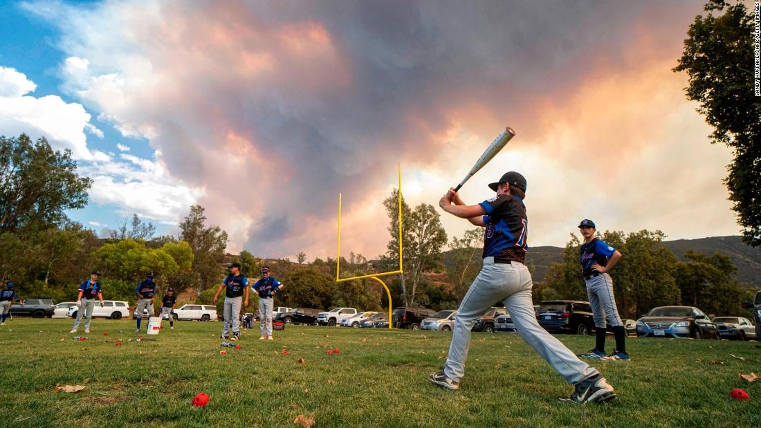 Little League baseball players warm up for a game near Dehesa, California, as the Valley Fire burns on September 6.