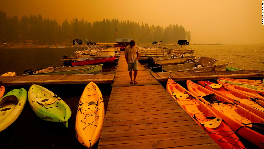 A business owner in Shaver Lake walks next to kayaks he rents as smoke from the Creek Fire fills the sky on September 6, 2020.