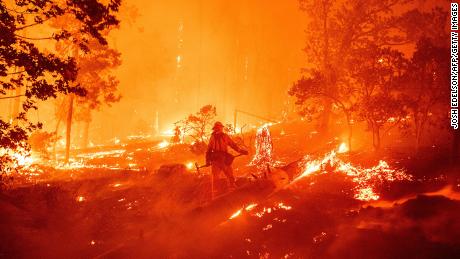 TOPSHOT - A firefighter works the scene as flames push towards homes during the Creek fire in the Cascadel Woods area of unincorporated Madera County, California on September 7, 2020. - A firework at a gender reveal party triggered a wildfire in southern California that has destroyed 7,000 acres (2,800 hectares) and forced many residents to flee their homes, the fire department said Sunday. More than 500 firefighters and four helicopters were battling the El Dorado blaze east of San Bernardino, which started Saturday morning, California Department of Forestry and Fire Protection (Cal Fire) said. (Photo by JOSH EDELSON / AFP) (Photo by JOSH EDELSON/AFP via Getty Images)