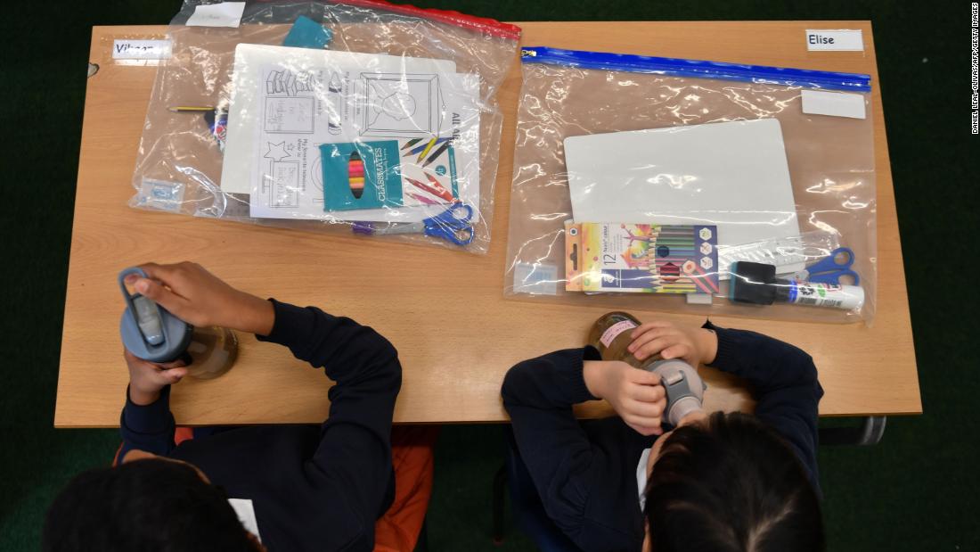 Students sit together on their first day of school in London on September 3. Their belongings had to be contained in plastic bags as part of new regulations.