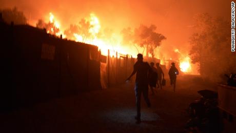 Refugees and migrants run as fire burns in the Moria refugee camp on the northeastern Aegean island of Lesbos, Greece, on Wednesday, Sept. 9, 2020. Fire Service officials say a large refugee camp on the Greek island of Lesbos has been partially evacuated despite a COVID-19 lockdown after fires broke out at multiple points around the site early Wednesday. (AP Photo/Panagiotis Balaskas)