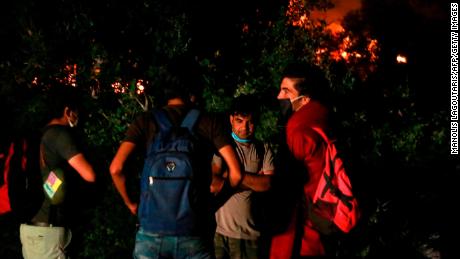 Migrants stand outside the Moria camp on the island of Lesbos as a major fire ravages the site. 