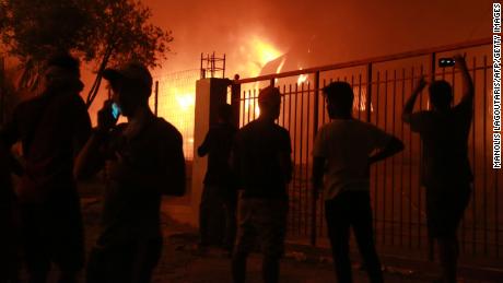 Migrants stand outside the Moria camp on the island of Lesbos during a major fire there on September 9, 2020. 