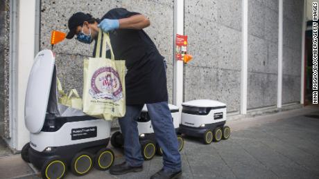 A worker loads groceries for delivery into a Starship Technologies Inc. robot in Mountain View, California, U.S., on Monday, May 18, 2020. Starship is a six-wheeled ground robot that can navigate streets and sidewalks autonomously, offering on-demand package delivery for consumers and businesses. Photographer: Nina Riggio/Bloomberg via Getty Images