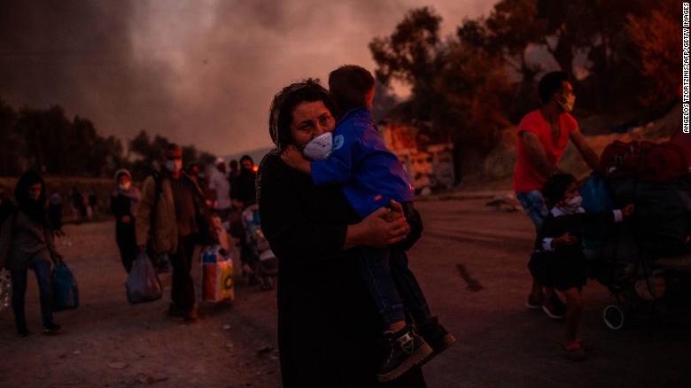 A woman carries a child after a fire broke out in the Moria migrants camp in Lesbos on September 9, 2020. 