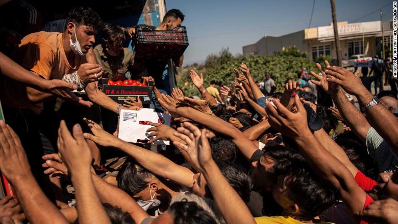 People jostle for food on Thursday, September 10, after fires destroyed the Moria migrant camp on the Greek island of Lesbos.