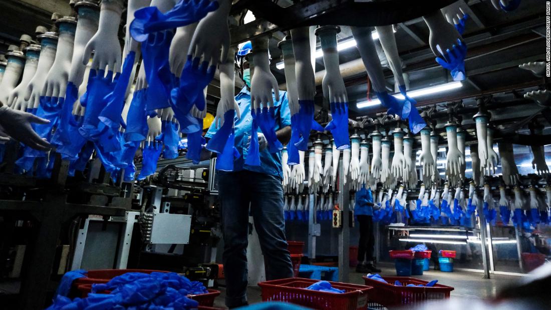 An employee monitors latex gloves on an automated production line at a Top Glove factory, February 18, 2020.