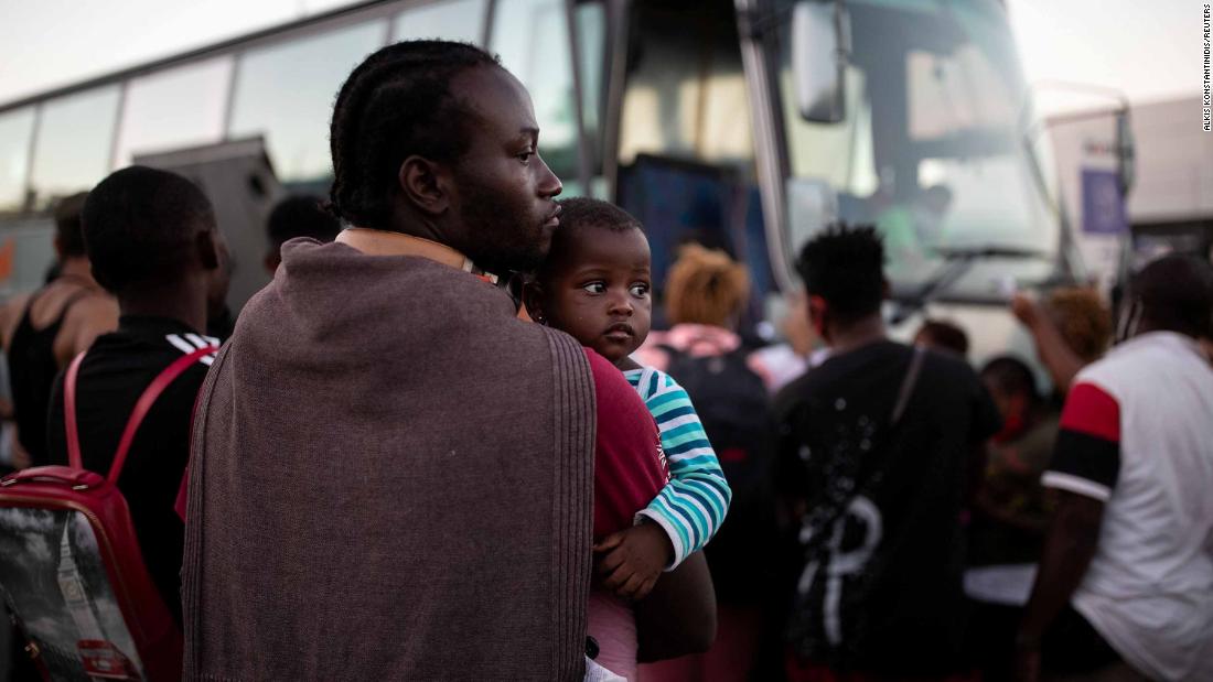 A man holds a baby as migrants wait to board a bus on Thursday, September 10.