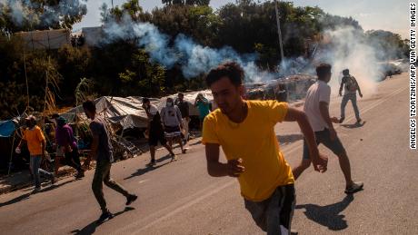 Refugees and migrants flee as tear gas is fired by riot police during clashes on Lesbos on September 12.