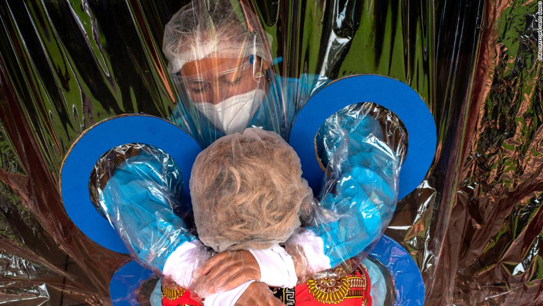 Maria Hernandez, top, embraces her aunt through a transparent curtain at a nursing home in San Salvador, El Salvador, on September 11.