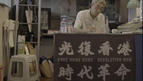 Lam Wing-kee in his Taipei book shop, where a banner displays slogans which have been declared subversive in Hong Kong.