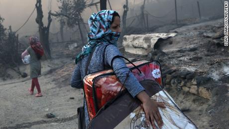 A migrant carries her belongings following the devastating blaze at the Moria camp on September 9.