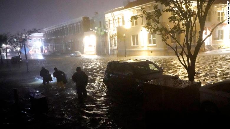 People walk on flooded streets in search of their vehicle early Wednesday in Pensacola, Florida.