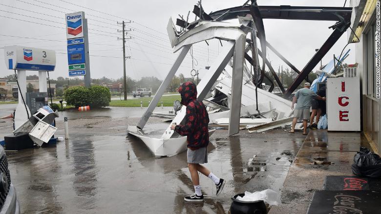 People stock up on ice and other items at a damaged convenience store near Spanish Fort, Alabama.