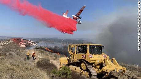 A bulldozer digs fire mine while a Cal Fire plane drops phos-check near a 110 acre fire by Vandenberg Air Force Base.