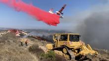 A bulldozer digs fire mine while a Cal Fire plane drops phos-check near a 110 acre fire by Vandenberg Air Force Base.