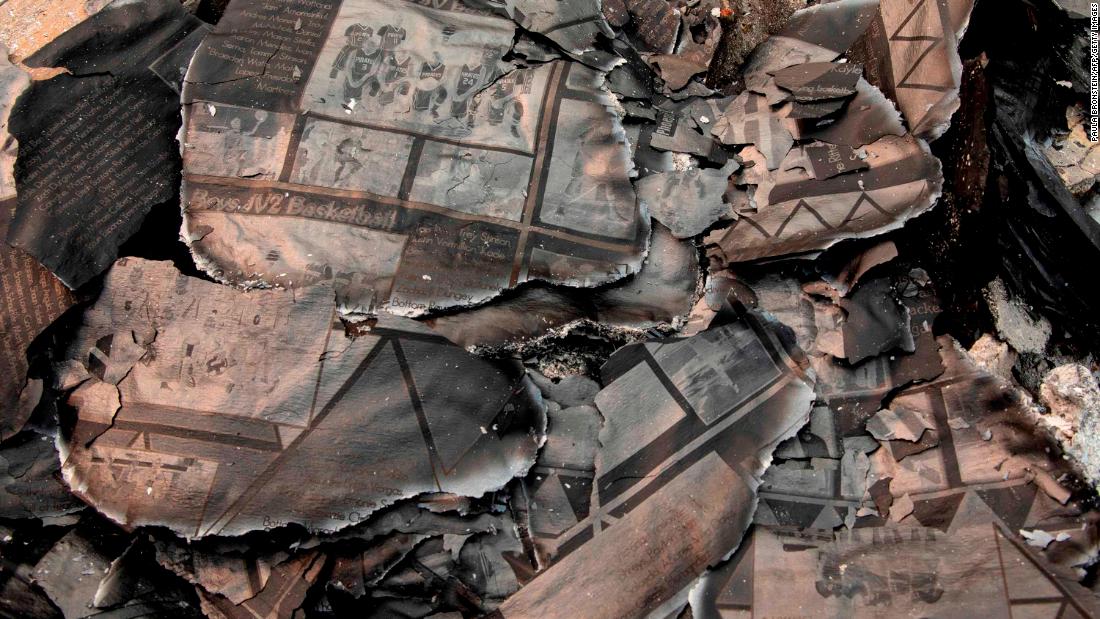 A charred yearbook lies in the debris as Fred Skaff and his son Thomas clean up their home in Phoenix, Oregon, on September 16, 2020.