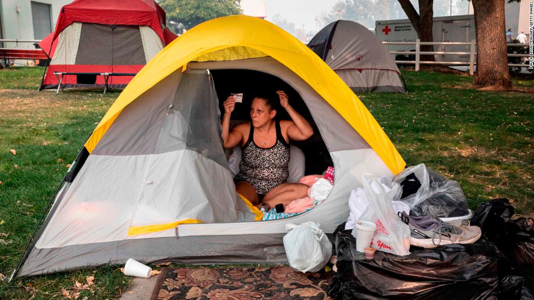 Stacey Kahny fixes her hair inside her tent at the evacuation center at the Jackson County Fairgrounds in Central Point, Oregon, on September 16, 2020. Kahny lived with her parents at a trailer park in Phoenix, Oregon, that was destroyed by fire.