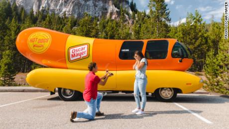 Zach Chatham proposes to his girlfriend beside the Wienermobile.