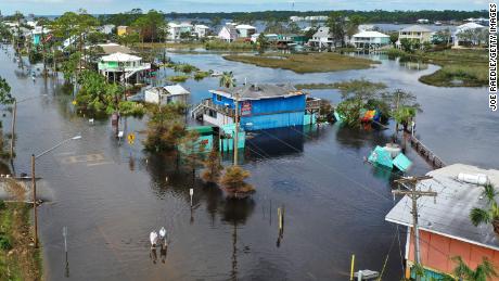 An aerial view from a drone shows people walking through a flooded street in Gulf Shores, Alabama.