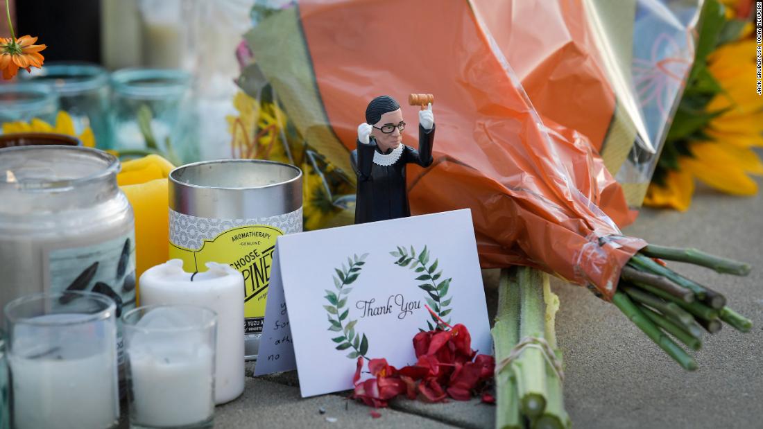 An action figure of Ginsburg is placed among cards, flowers and candles at her makeshift memorial outside of the Supreme Court.