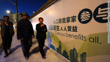 Pedestrians walk past a billboard for China&#39;s last national population census on October 29, 2010 in Beijing.