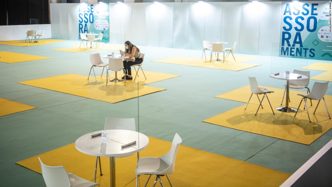 An adviser waits for people behind a plastic glass screen during a job fair in Barcelona, Spain, on September 21.