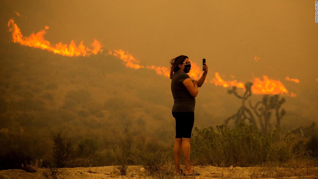 A woman takes photos as the Bobcat Fire burns in Juniper Hills, California, on September 18.