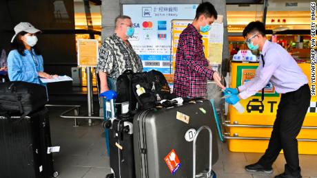 Un trabajador rocía desinfectante de manos a los pasajeros cuando llegan al aeropuerto de Taoyuan en Taiwán.