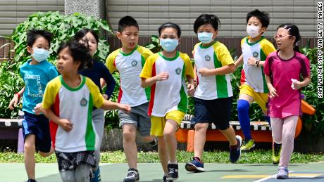 Students wearing face masks run during a sports class at Dajia Elementary School in Taipei on April 29, 2020. 