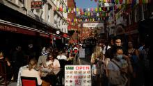 People sit outside in Chinatown, central London, on Saturday. The UK has introduced a 10 p.m. curfew for pubs and restaurants.