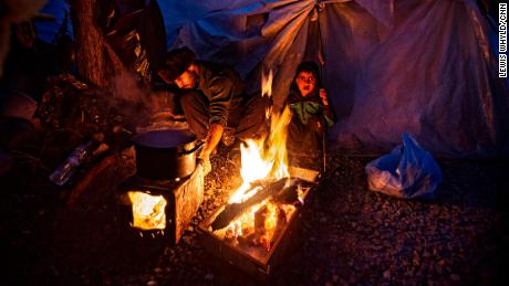 People gather around a fire for warmth in the Moria refugee camp in Lesbos, Greece in February 2020.